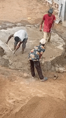 Three workers hand-mix cement at construction site