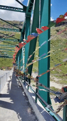Prayer flag bridge over a mountain river valley in northern India