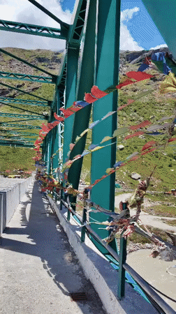 Prayer flag bridge over a mountain river valley in northern India