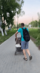 Woman takes selfies, man pushes stroller in Chaikovsky walkways