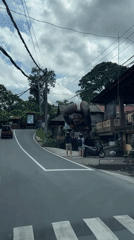 Vehicle stops at pedestrian crossing near statue in Tegallalang, Bali