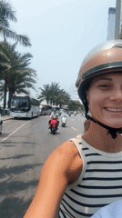 Woman flashes peace signs while motorcycling through Đà Nẵng traffic