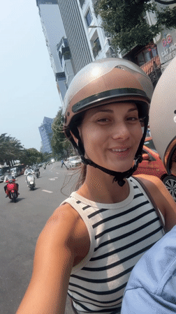 Woman flashes peace signs while motorcycling through Đà Nẵng traffic