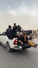 Armed men in traditional dress travel by truck in Pakistan