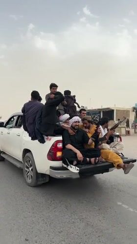 Armed men in traditional dress travel by truck in Pakistan