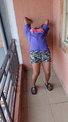 Woman does morning stretches on balcony in Obinagu, Nigeria