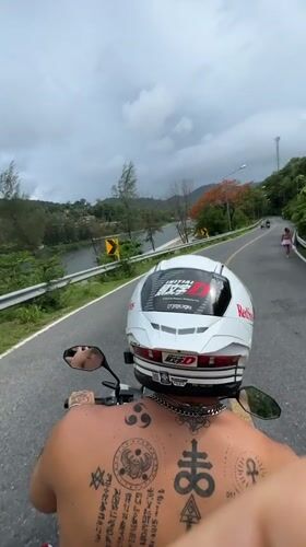 Couple rides motorcycle through Rawai Thailand early morning