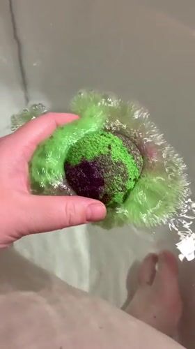 Green bath bomb dissolves into a candlelit tub in Hrodna
