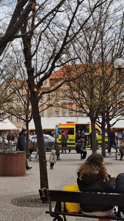 Ambulance with open doors stationed in busy Prague square