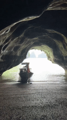 Cave mouth frames a red-canopied boat on Thai waters