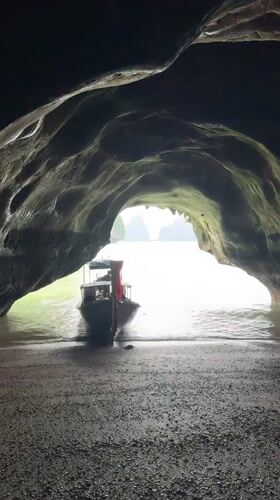 Cave mouth frames a red-canopied boat on Thai waters