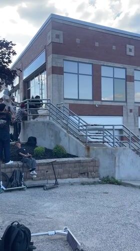 Scooter crew hits stair spot outside London, Canada brick building