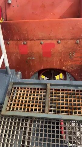 The camera moves around an orange boat, focusing on the propellers spinning in the water under the boat, and then moves to the door of the boat that is open.