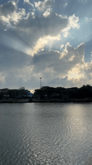 Sunbeams pierce cloudy sky over water in Baan Chaweng