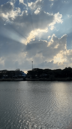Sunbeams pierce cloudy sky over water in Baan Chaweng