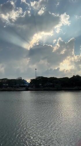 Sunbeams pierce cloudy sky over water in Baan Chaweng