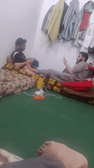 Two men converse on floor mattresses in Peshawar room