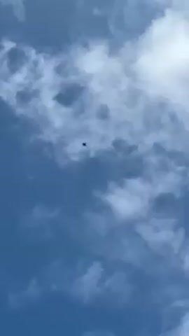Here is a concise description of the video: 

The video shows an airplane high in the sky. The sky is blue with puffy white clouds.