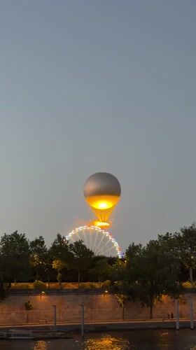 Hot air balloon and Ferris wheel light up Paris at dusk