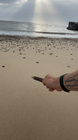 Person draws in sand at East Suffolk beach