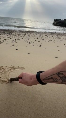 Person draws in sand at East Suffolk beach