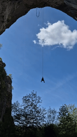 Person rappels from stone arch in Karlukovo, Bulgaria