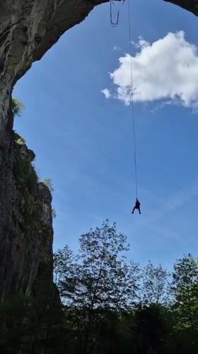 Person rappels from stone arch in Karlukovo, Bulgaria