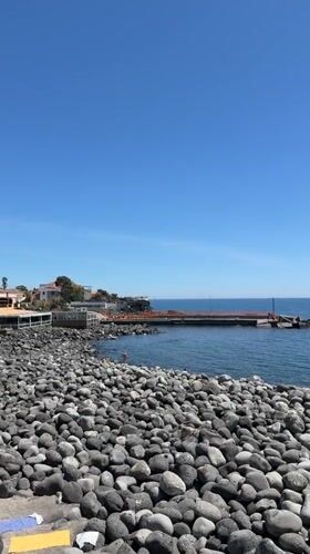 Clear day captured on Catania's dark stone beach