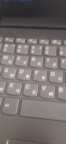 A close-up shot displays the keyboard of a black Lenovo laptop. The keys are gray with white lettering and show both Latin and Cyrillic characters. The lighting is even, and the camera remains still throughout the shot. The keyboard appears slightly dusty. No actions or interactions occur in the frame.
