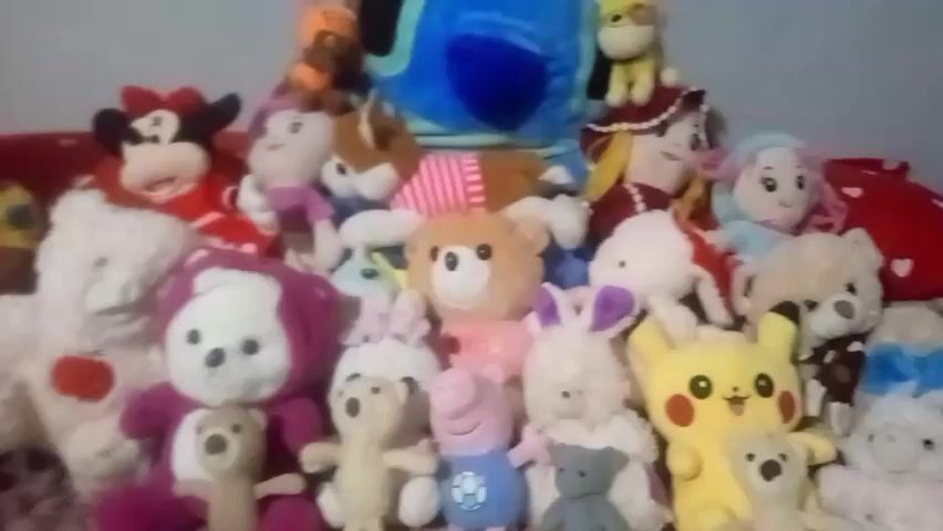 This media file is a close-up, slightly blurry video of a collection of stuffed animals. The stuffed animals are arranged on a surface that appears to be a bed, covered with a patterned blanket. The lighting suggests an indoor setting, likely during the day, though no windows are visible.

The subjects are a diverse assortment of plush toys, including recognizable characters like Minnie Mouse, Stitch, Pikachu, and Peppa Pig, alongside generic teddy bears and other animal figures. The toys vary in size, color, and design, creating a vibrant and playful scene. Many of the stuffed animals are facing the camera, some appearing to have slightly tilted heads, giving the impression of a posed display.

There is no discernible activity or event taking place; the scene is static, focusing solely on the collection of toys.

Notable details include the wide variety of characters, suggesting a personal collection. The overall impression is one of innocence and childlike joy, as is typical with a collection of stuffed animals. There is no visible text in the video. The implied location context of Marhamat, Uzbekistan, is not visually evident from the media itself.