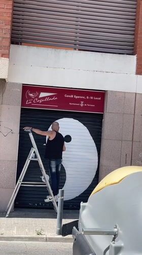 Artist paints yin yang symbol on storefront in Terrassa