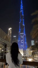Woman views illuminated Burj Khalifa from Dubai balcony