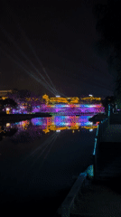 Colorful night lights illuminate traditional bridge in Wulingyuan waterway