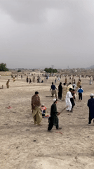 Children play in dusty Quetta neighborhood, one flying kite