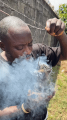Man performs smoking ritual outdoors in Ado, Nigeria