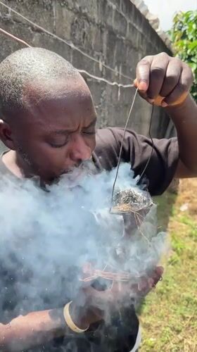 Man performs smoking ritual outdoors in Ado, Nigeria