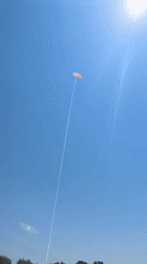 Colorful kite flying over Fethiye's pebble beach on a sunny morning