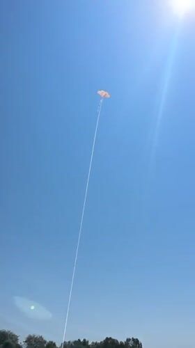 Colorful kite flying over Fethiye's pebble beach on a sunny morning