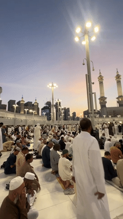 Worshippers in white gather on tiled ground in Makkah