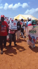 Outdoor political rally with signs, banners, and a crowd