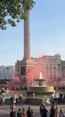 Crowd gathers with red smoke in London's Trafalgar Square