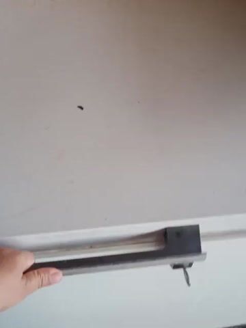 A person's hand opens a freezer door, revealing a densely packed freezer filled with various food items in plastic containers and bags. The food appears to be frozen.