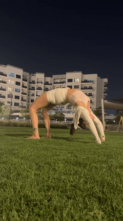 Woman performs yoga wheel pose on Dubai lawn