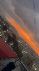 Dusk cityscape with orange clouds filmed from Caracas rooftop
