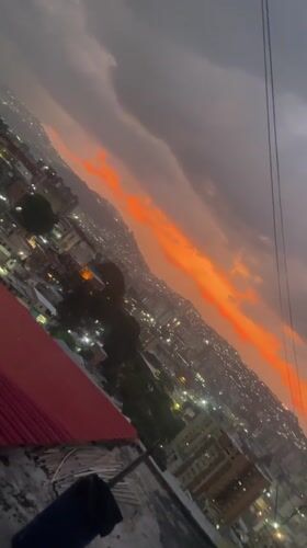 Dusk cityscape with orange clouds filmed from Caracas rooftop
