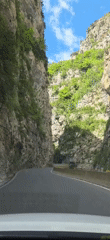 Car drives through rocky gorge on winding road in Spain
