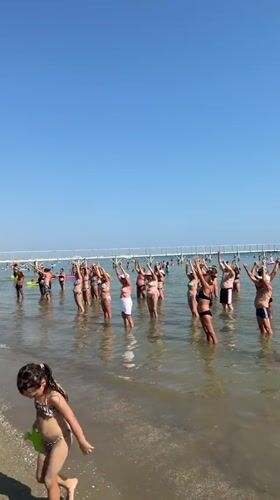 Group water aerobics and beach crowds on a sunny Gatteo morning