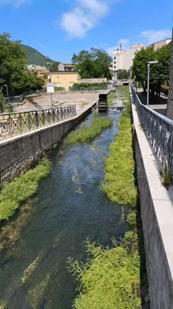 Stone canal and shaded walkway along Bojano's waterway