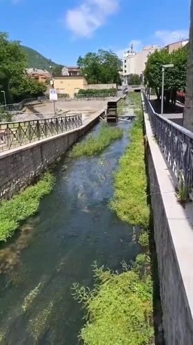 Stone canal and shaded walkway along Bojano's waterway