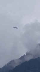 Helicopter over cloudy, forested peaks near Vashisht